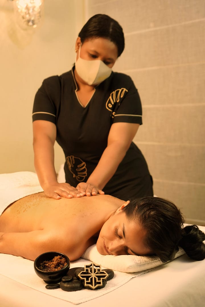 Mujer recibiendo exfoliación y relajación con piedras calientes en el spa de un hotel de lujo.